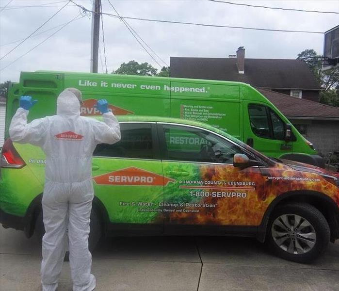 SERVPRO employee in PPE standing in front of our SERVPRO vehicles ready to work