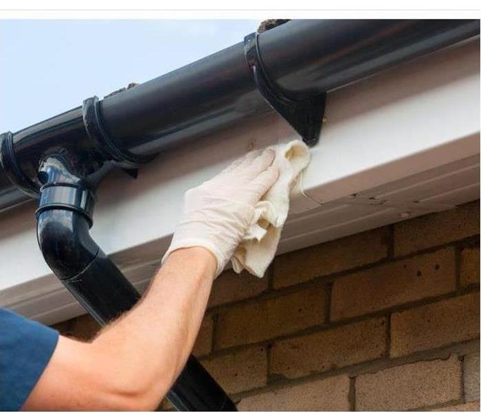 Cleaning gutter with a rag and gloves