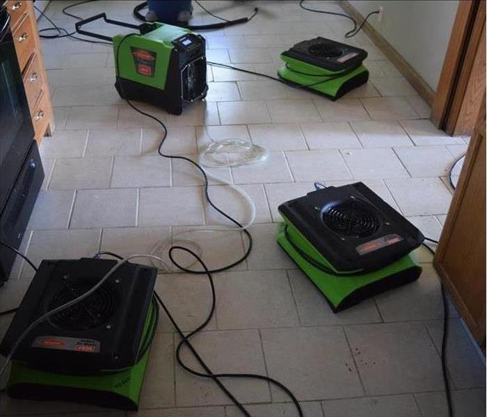 Drying equipment (air movers and dehumidifiers) placed on a kitchen that was damaged by water
